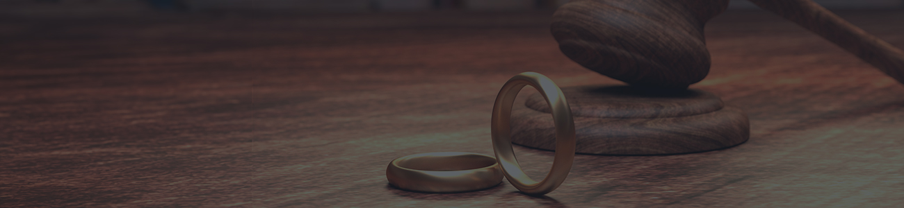 A wooden gavel rests beside a wedding ring on a table